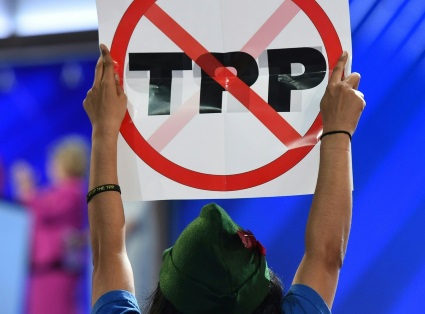 someone in a Robin Hood hat holds up an anti-TPP sign