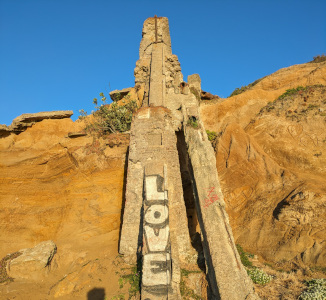 A ruined tower in a sandstone cliff is graffiti'd with "LOVE" and set against a dark blue sky