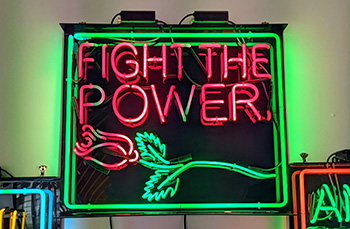 a neon sign with a red rose reading "fight the power"