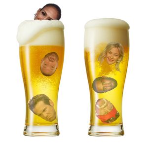 Two full beer steins in which the heads of famous people float: Hulk Hogan, Sean "Puffy" Combs, Kate Hudson, Ryan Reynolds, Conor McGregor, and Jennifer Lopez just peeking out above the foam.
