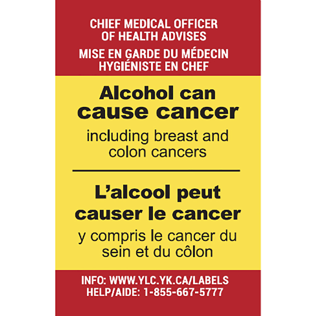 A red-and-yellow warning label that says "chief medical officer of health advises - mise end garde du medecin hygieniste en chef - Alcohol can cause cancer including breast and colon cancers - L'alcool peut causer le cancer y compris le cancer du sein et du colon - info: www.ylc.yk.ca/labels/help/aide: 1-855-667-5777